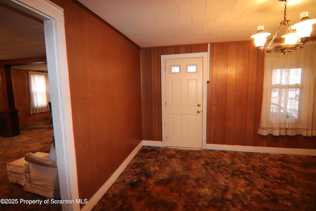 foyer entrance with a chandelier and wood walls