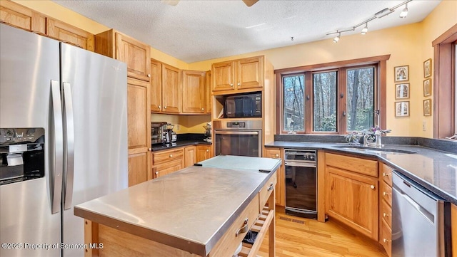 141 Cove Point Cir, Lakeville, PA 18438 - kitchen featuring appliances with stainless steel finishes, a sink, light wood-style flooring, a center island, and dark countertops