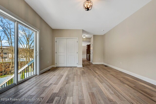 interior space with a closet, an inviting chandelier, access to outside, and light hardwood / wood-style flooring