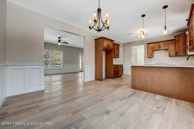 kitchen featuring light wood finished floors, brown cabinetry, a ceiling fan, open floor plan, and a peninsula