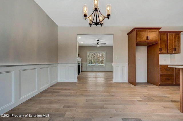 unfurnished dining area featuring ceiling fan with notable chandelier and light hardwood / wood-style floors