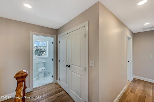 corridor with light wood finished floors, visible vents, baseboards, and recessed lighting