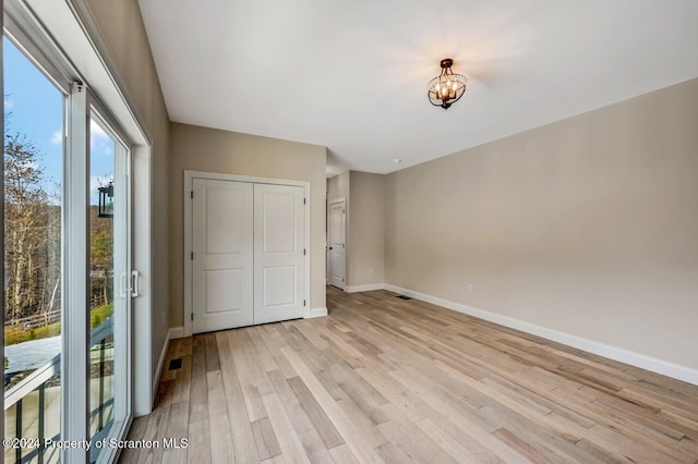 unfurnished bedroom with light hardwood / wood-style floors, access to exterior, and a closet