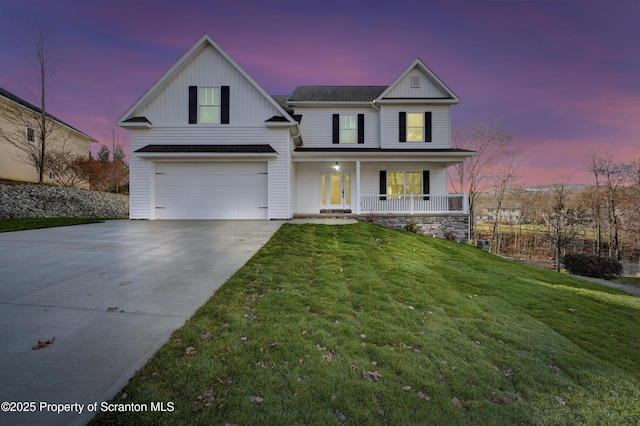 view of front facade with driveway, covered porch, a lawn, and board and batten siding