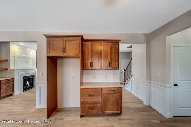 kitchen featuring light countertops, a decorative wall, light wood-style flooring, and brown cabinets