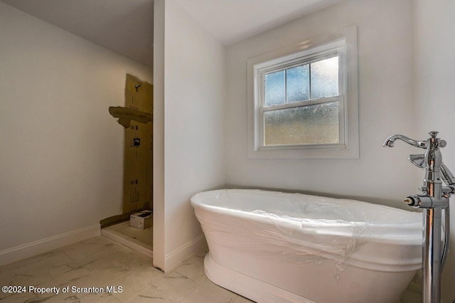 bathroom featuring marble finish floor, a shower stall, baseboards, and a soaking tub