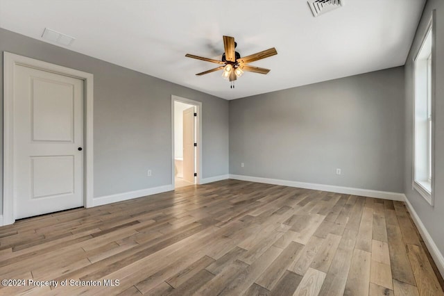 spare room featuring baseboards, visible vents, ceiling fan, and light wood finished floors