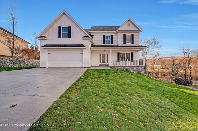 view of front of house featuring a porch, a garage, and a front lawn