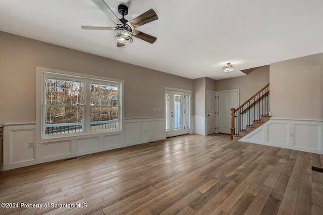 entryway featuring a ceiling fan, a decorative wall, stairway, and wood finished floors