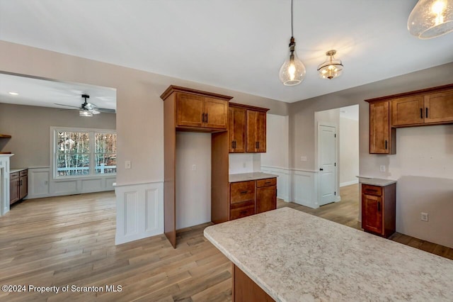 kitchen featuring light wood-type flooring, ceiling fan with notable chandelier, and hanging light fixtures