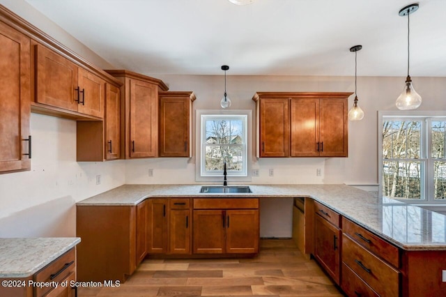 kitchen with a peninsula, brown cabinetry, a sink, and a wealth of natural light