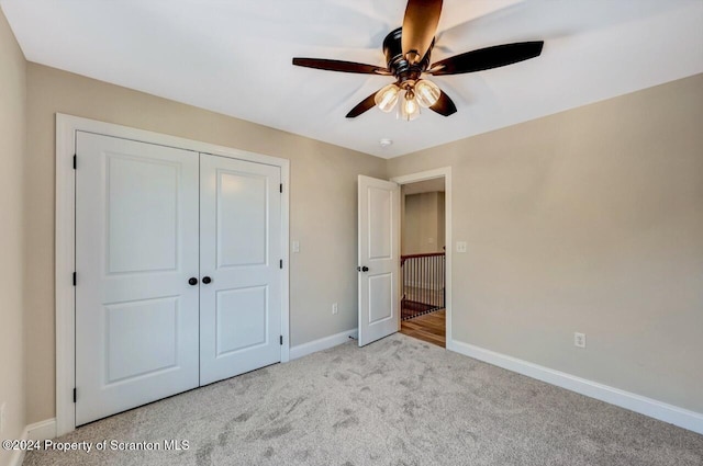 unfurnished bedroom with ceiling fan, a closet, and light carpet