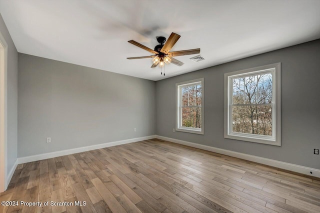 spare room featuring a ceiling fan, wood finished floors, visible vents, and baseboards