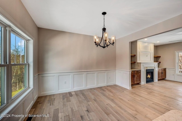 interior space featuring light wood-style flooring, wainscoting, and a lit fireplace