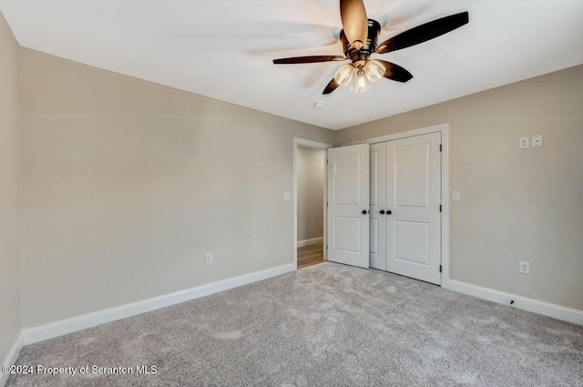 unfurnished bedroom with ceiling fan, light carpet, and a closet