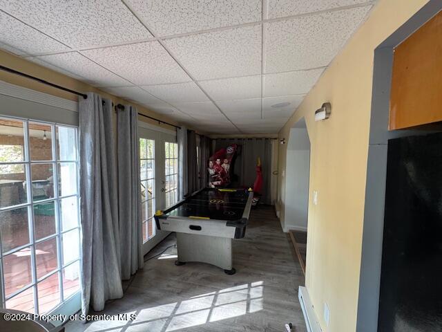 interior space with a drop ceiling, a baseboard heating unit, and french doors