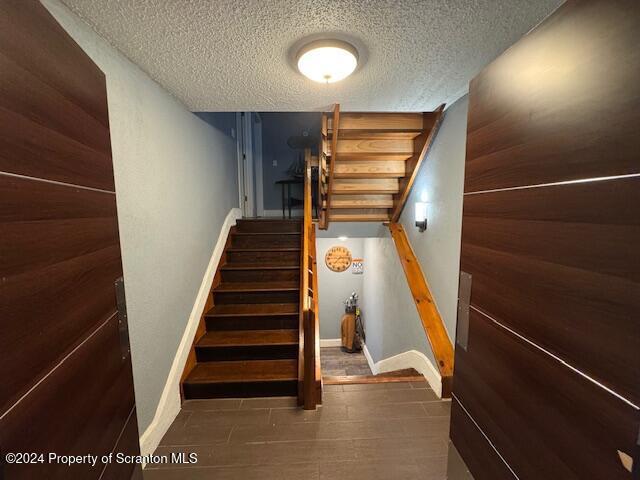 staircase with a textured ceiling and wood walls