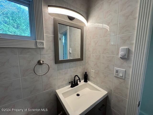 bathroom featuring backsplash, vanity, and tile walls