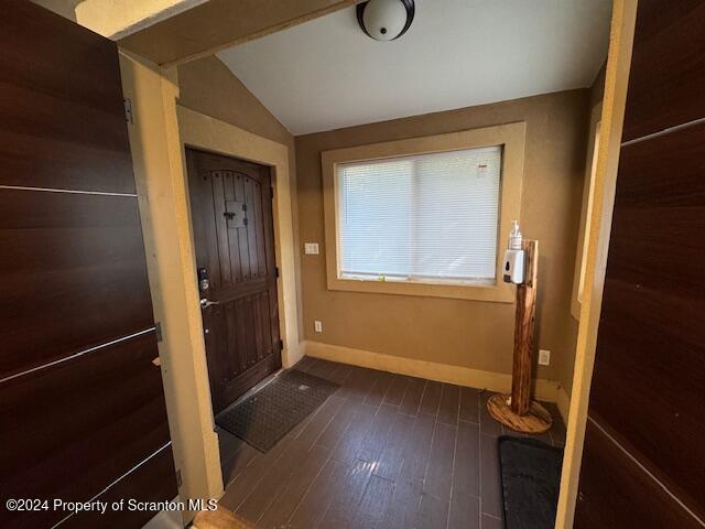 foyer featuring dark wood-type flooring and lofted ceiling