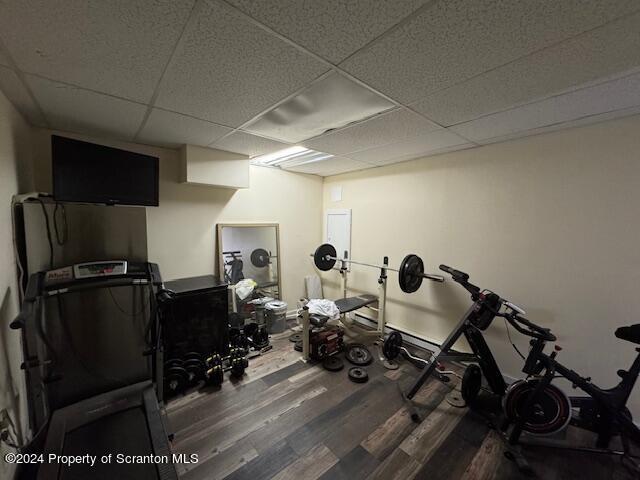 workout room with a paneled ceiling and dark wood-type flooring