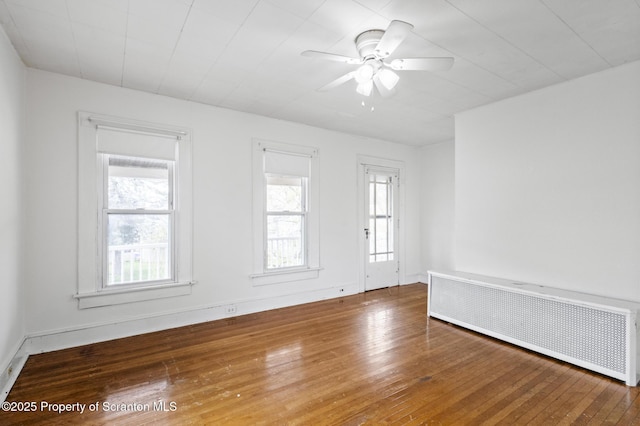 unfurnished room featuring radiator, a ceiling fan, and hardwood / wood-style floors