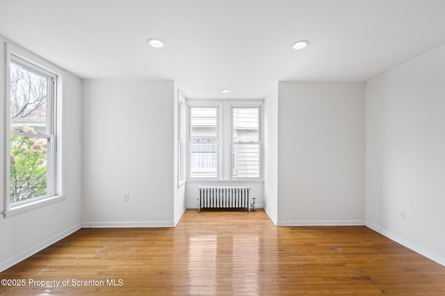 spare room with recessed lighting, baseboards, radiator heating unit, and light wood-style flooring