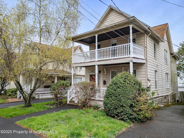 view of front of home featuring covered porch, a shingled roof, and a balcony