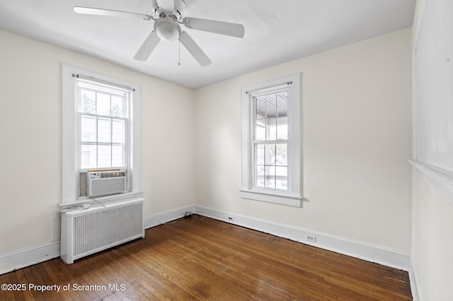 spare room with a ceiling fan, hardwood / wood-style flooring, baseboards, cooling unit, and radiator
