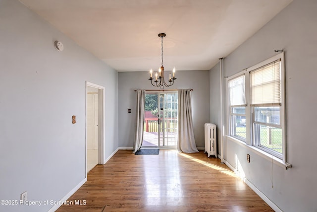 15 Leonard St, Wilkes-Barre, PA 18702 - unfurnished dining area featuring radiator heating unit, a chandelier, healthy amount of natural light, and wood finished floors
