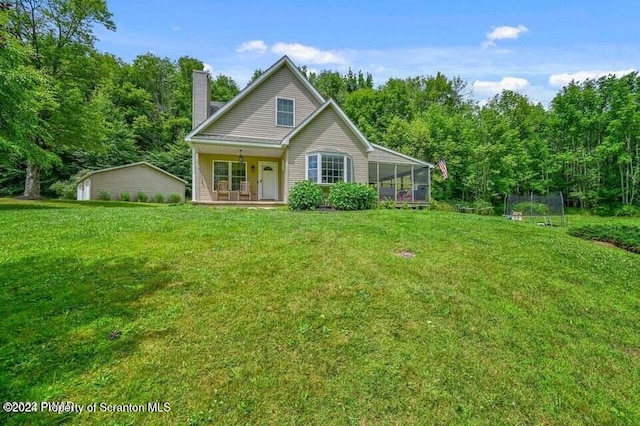 rear view of house with a lawn, a sunroom, a porch, and a trampoline