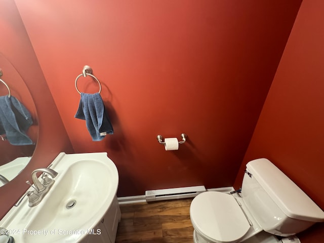 bathroom with toilet, sink, hardwood / wood-style floors, and a baseboard heating unit