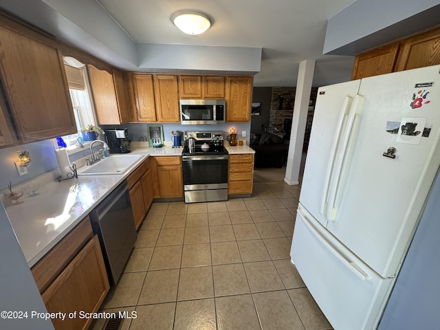 kitchen featuring a fireplace, light tile patterned flooring, sink, and appliances with stainless steel finishes