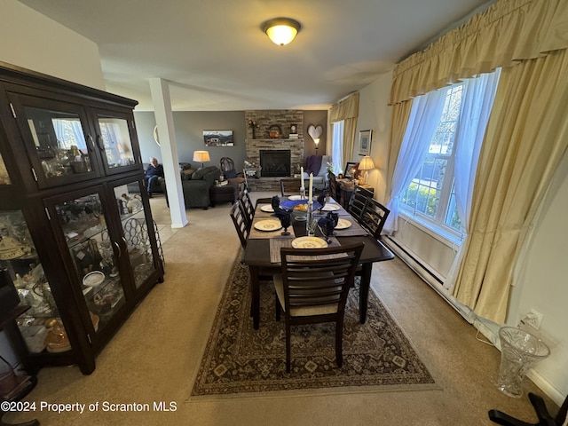 dining area featuring a stone fireplace and carpet floors