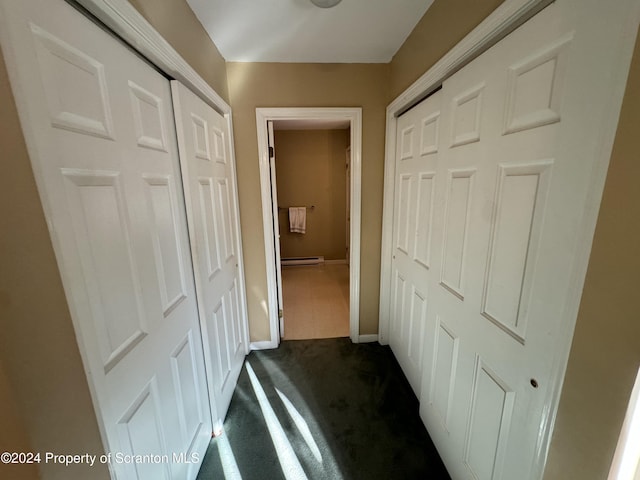 hallway with baseboard heating and dark colored carpet