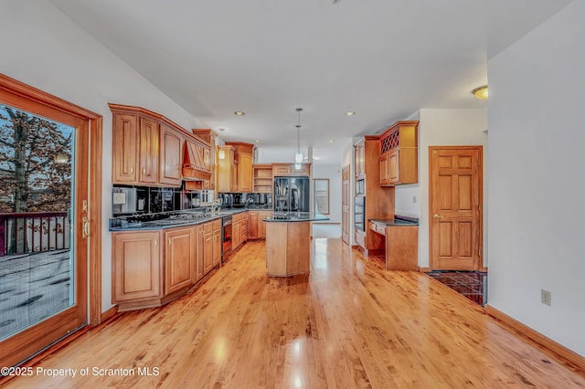 kitchen with a kitchen island, black appliances, light wood finished floors, brown cabinetry, and decorative light fixtures