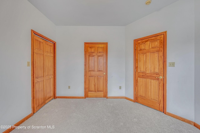 unfurnished bedroom featuring light colored carpet and baseboards