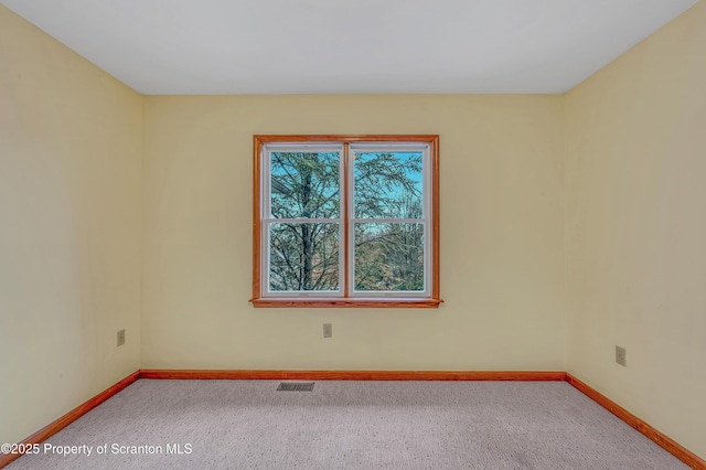 carpeted spare room with visible vents and baseboards