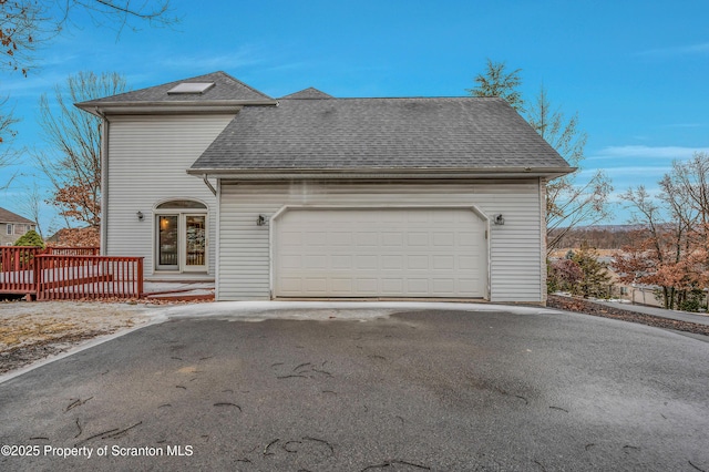 view of front of home featuring driveway, a shingled roof, a garage, and a deck