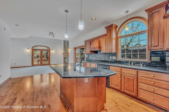 kitchen featuring a sink, black dishwasher, open floor plan, a center island, and pendant lighting