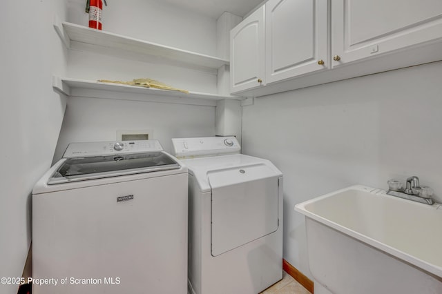 clothes washing area with cabinet space, washer and dryer, and a sink