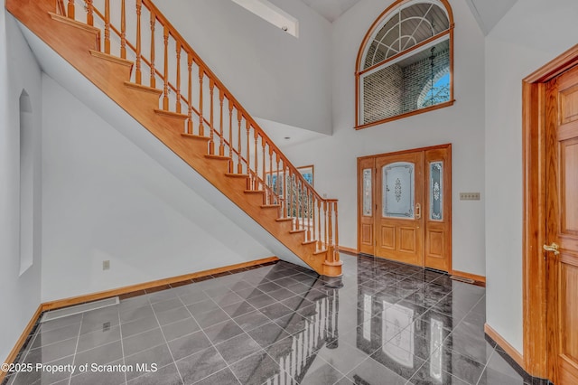 foyer with a high ceiling, stairway, granite finish floor, and baseboards