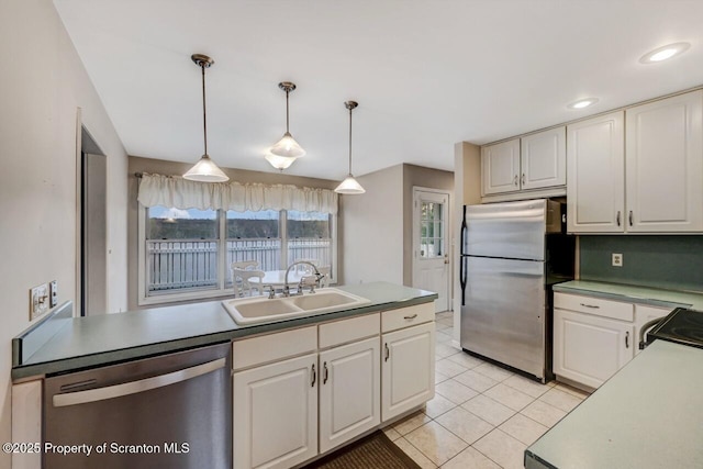 kitchen with a sink, light tile patterned flooring, pendant lighting, light countertops, and appliances with stainless steel finishes