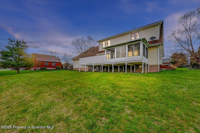 back of property with a sunroom and a lawn