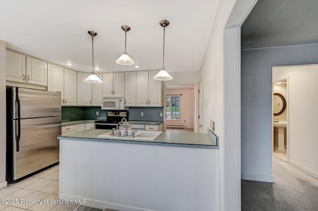 kitchen featuring pendant lighting, baseboards, a sink, a peninsula, and stainless steel appliances