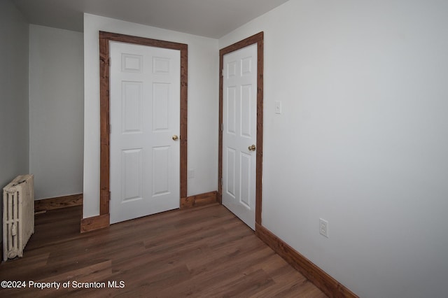 unfurnished bedroom featuring radiator heating unit, dark hardwood / wood-style flooring, and a closet