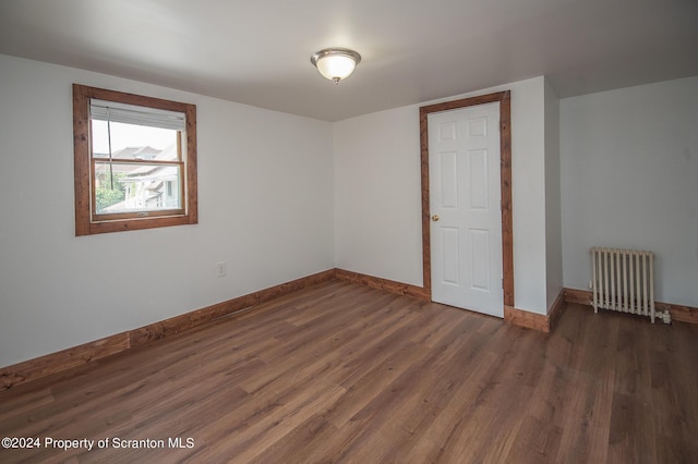 unfurnished room featuring radiator and dark wood-type flooring