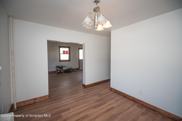 empty room featuring an inviting chandelier and dark wood-type flooring