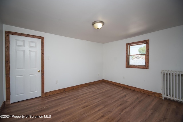 unfurnished room featuring radiator and dark wood-type flooring