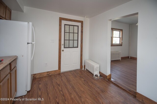 kitchen with radiator heating unit, white fridge, and dark wood-type flooring