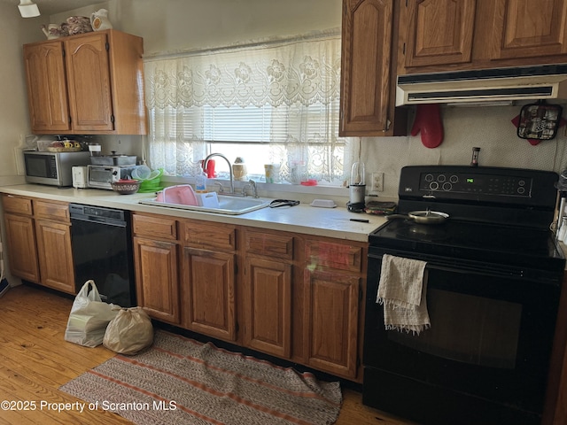 kitchen with sink, black appliances, and light wood-type flooring